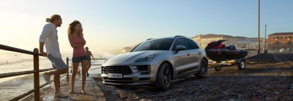 2019 Porsche Macan parked beachside with a jet ski in tow